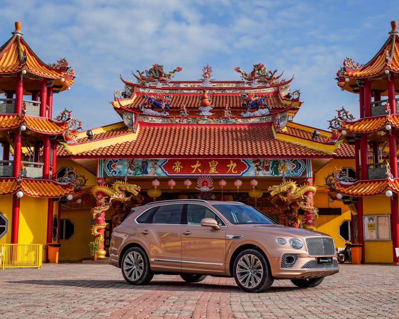 Коричневый автомобиль Bentley Bentayga V8 2020 года на фоне красивого здания