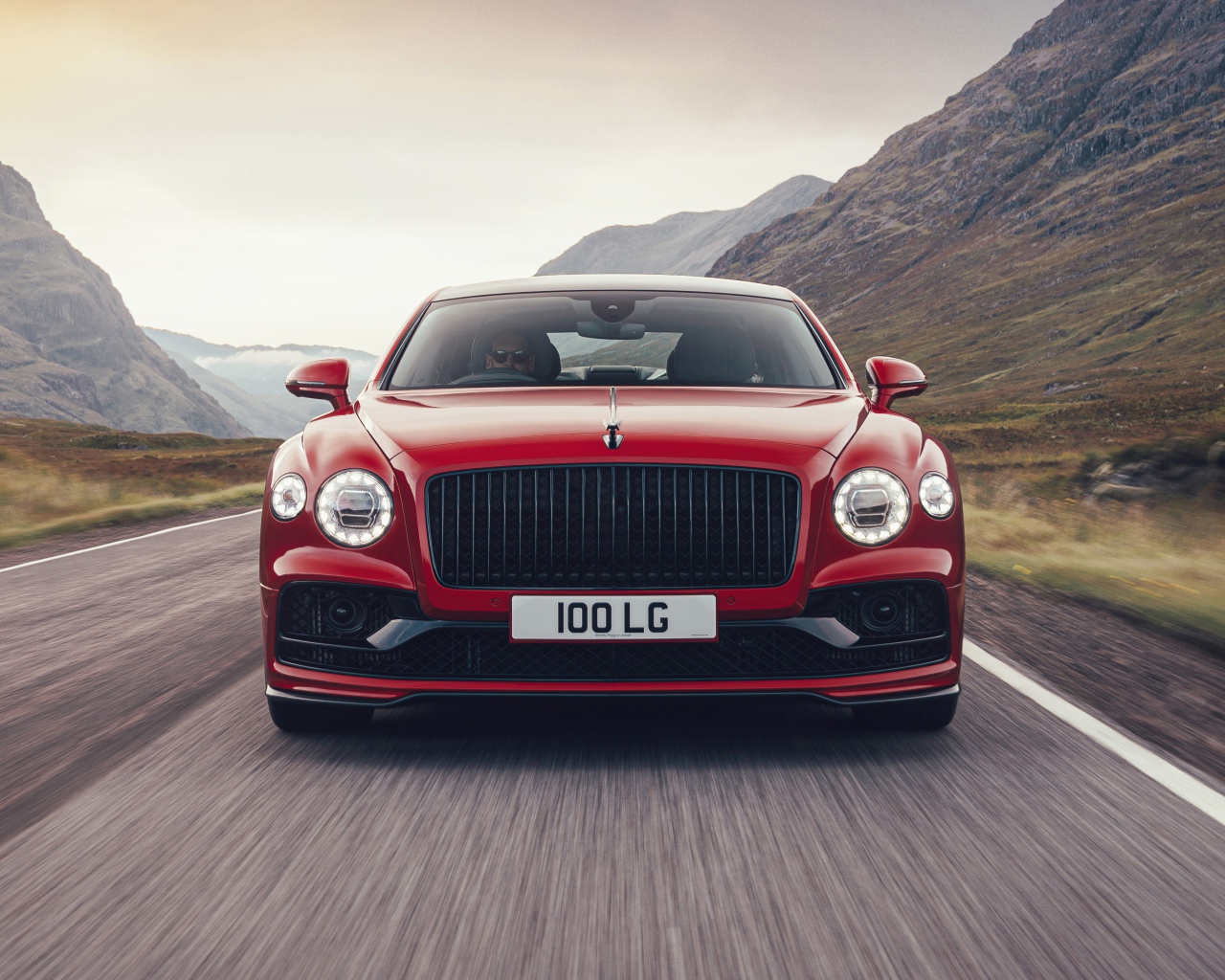 Красный автомобиль Bentley Flying Spur V8 2020 года на дороге в горах 