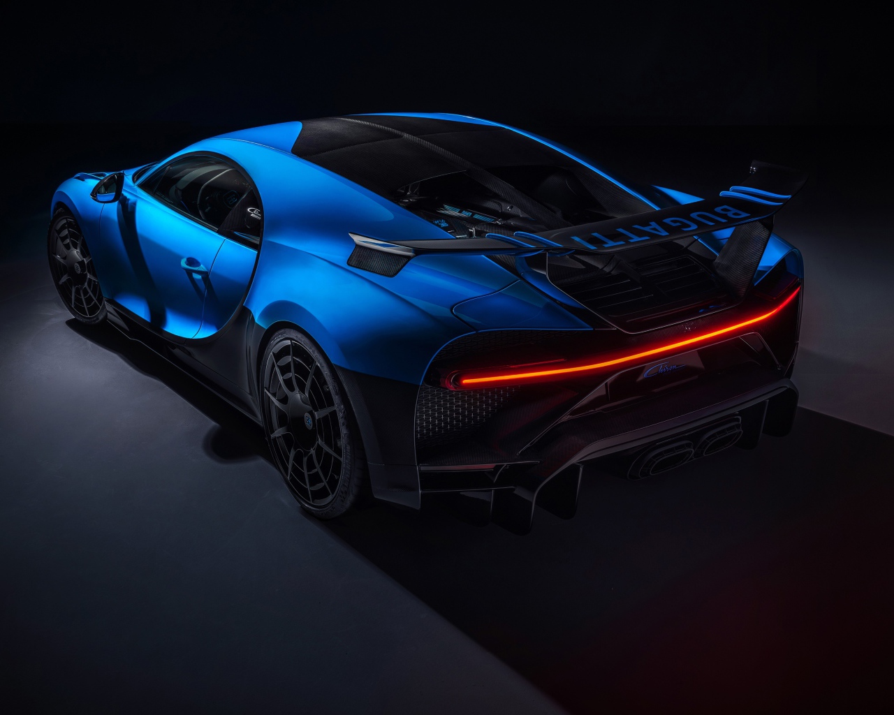 Синий автомобиль Bugatti Chiron Pur Sport 2020 года вид сзади на черном фоне