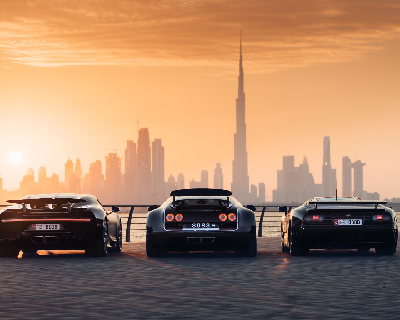 Три автомобиля  Bugatti Veyron и Bugatti Chiron на фоне заката