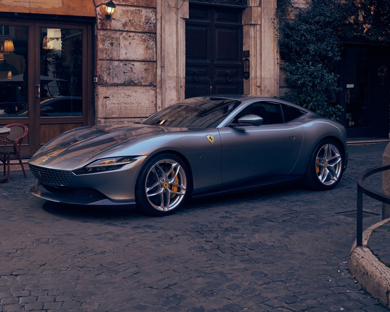 Серебристый автомобиль Ferrari Roma 2020 года у кафе