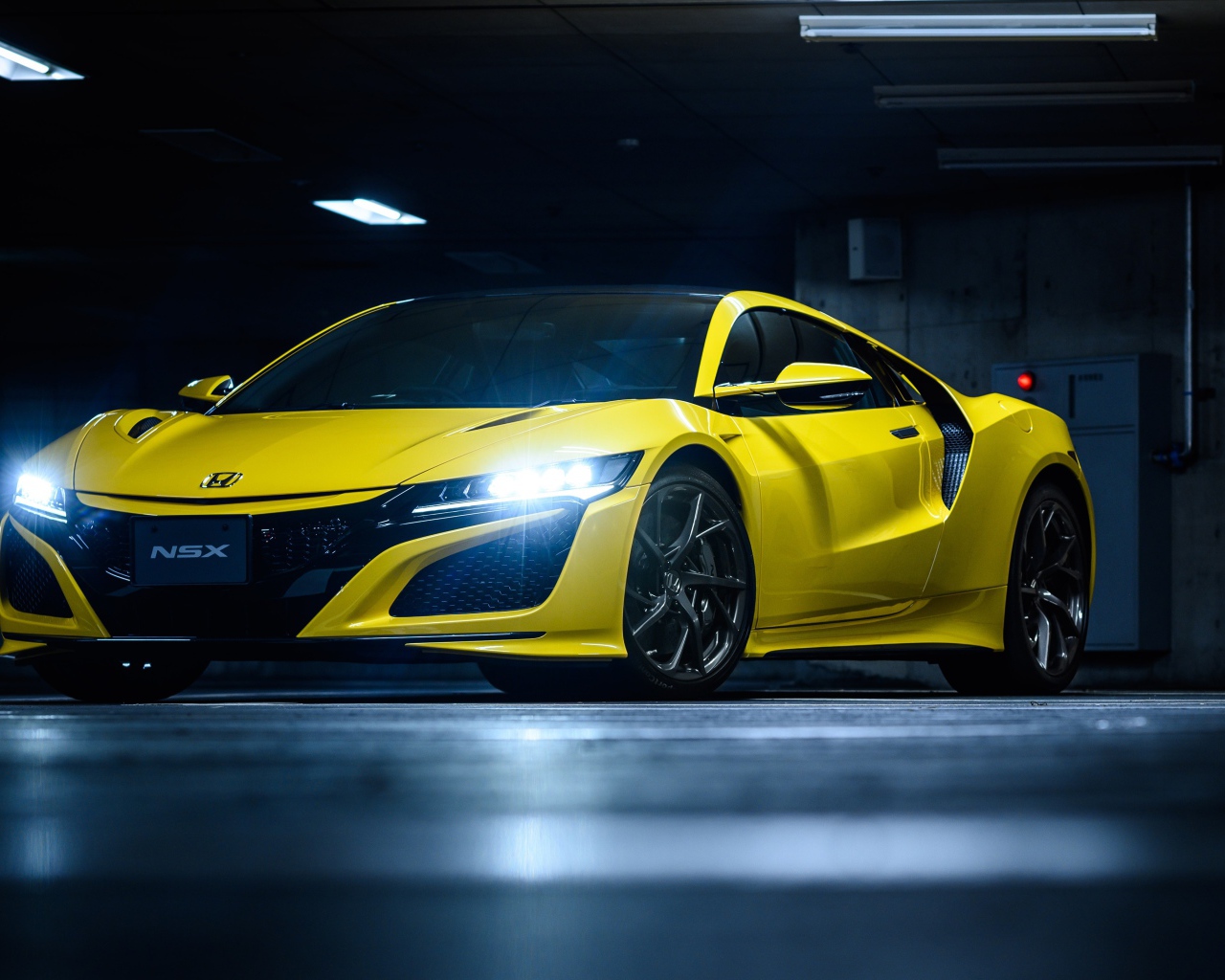 Желтый автомобиль Honda NSX с включенными фарами 