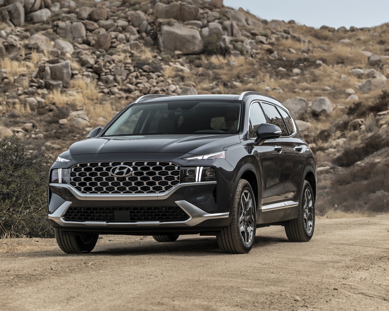 Черный автомобиль  Hyundai Santa Fe Hybrid, 2021 года у камней