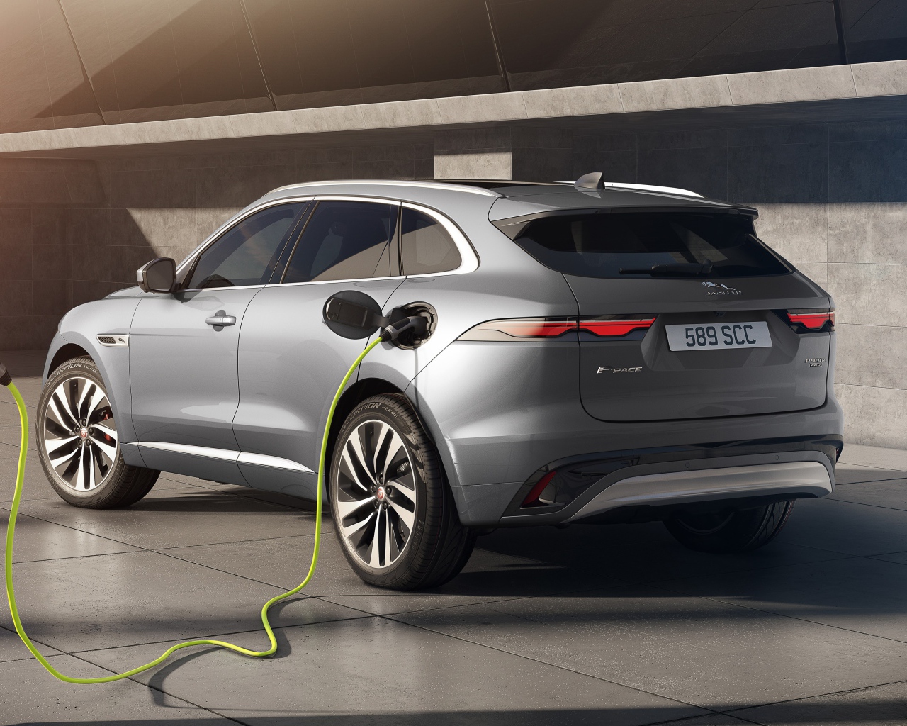 Серебристый автомобиль Jaguar F-Pace P400e AWD 2020 года на заправке 