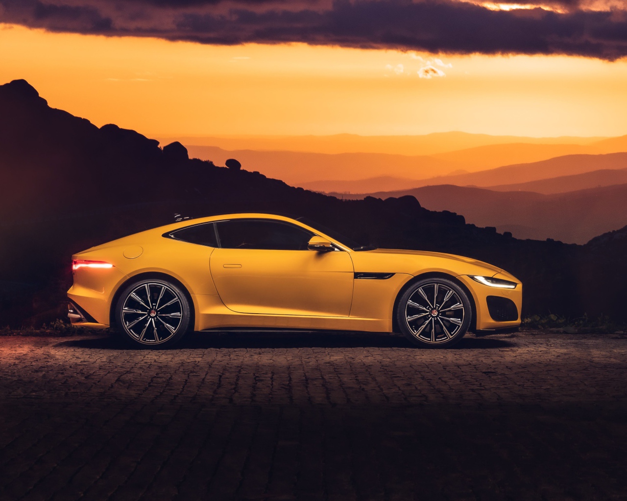 Желтый автомобиль jaguar f type 2020 года на закате 