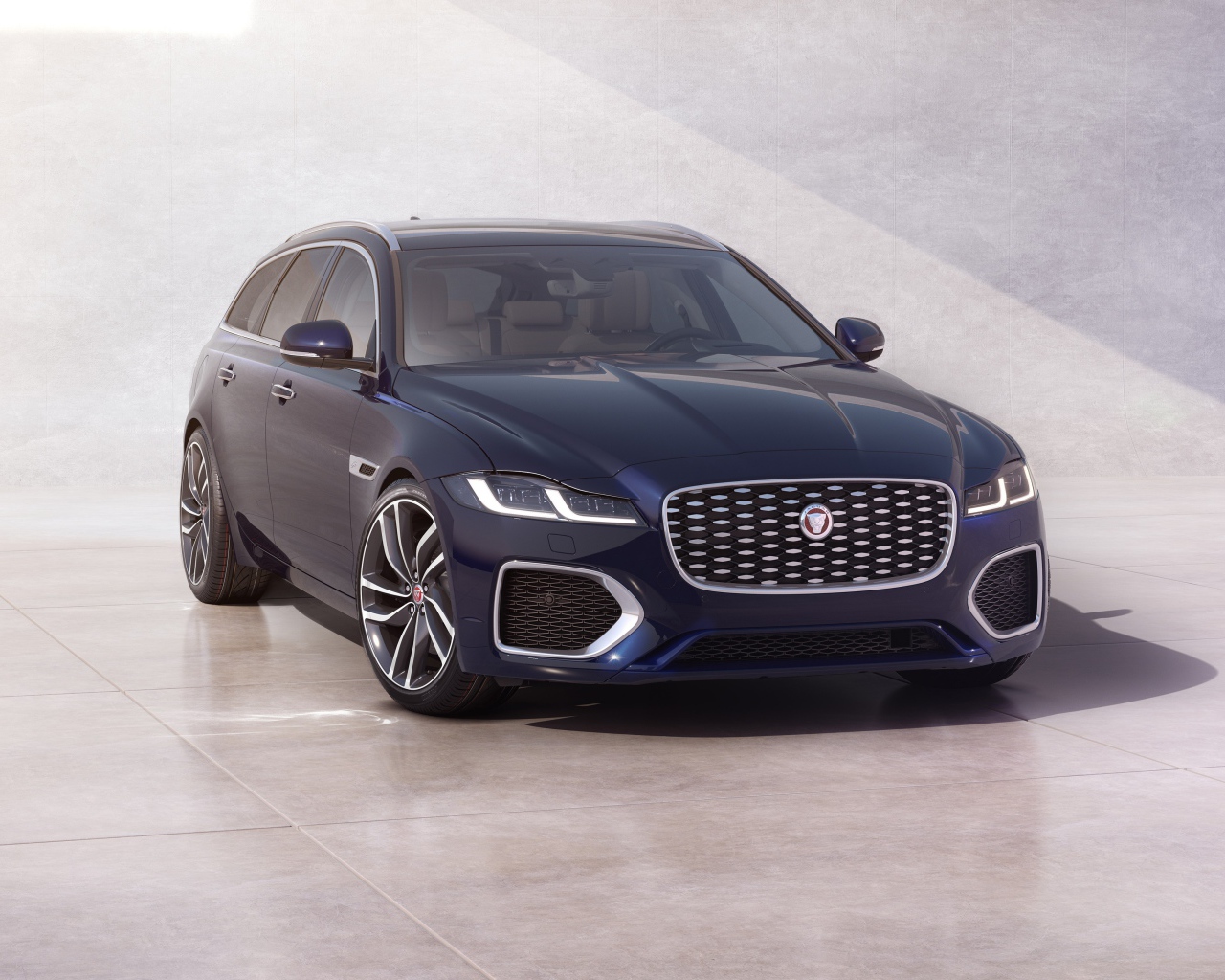 Синий автомобиль Jaguar XF Sportbrake 2020 года у стены 