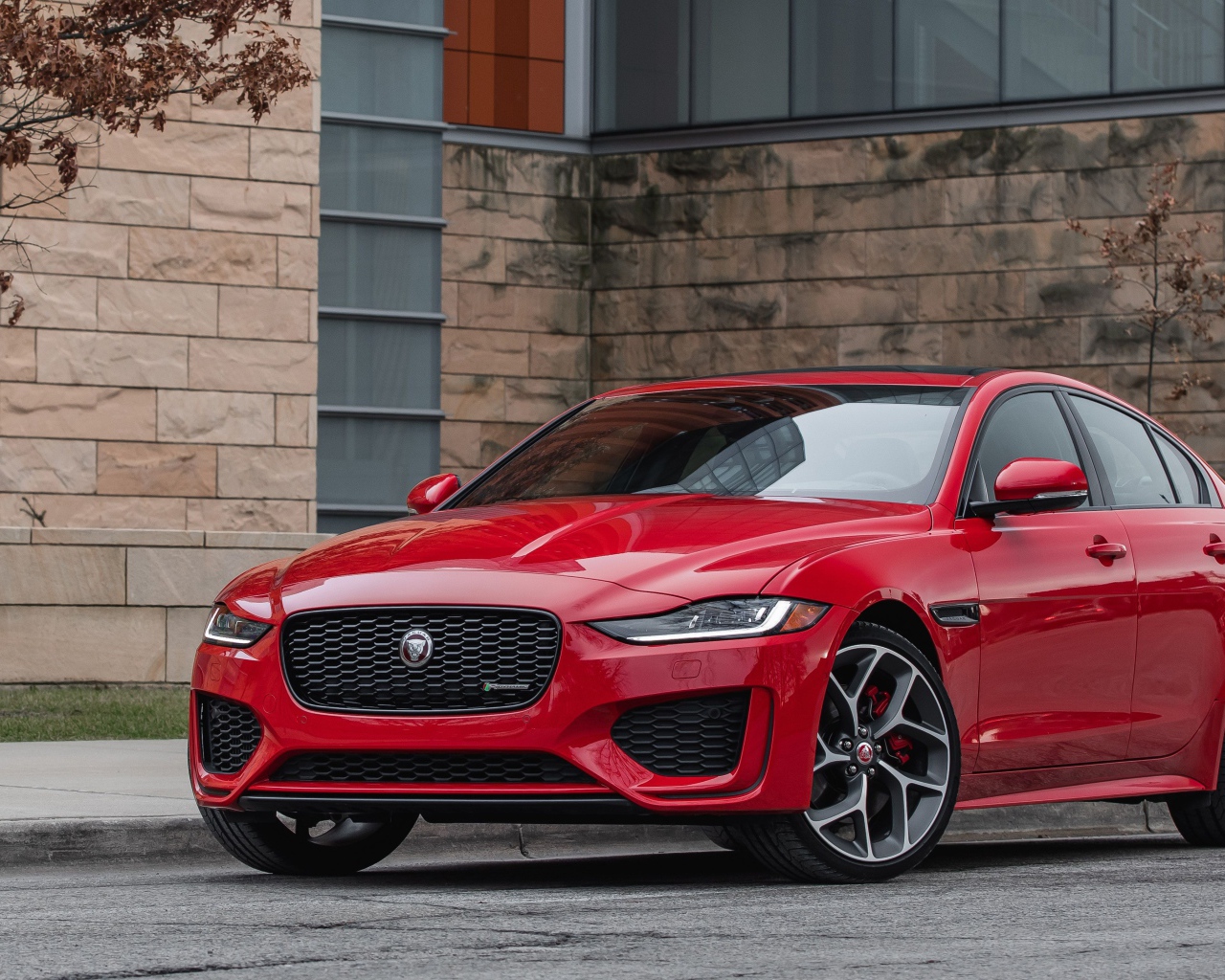 Красный автомобиль Jaguar XE P300 R-Dynamic, 2020 года у здания