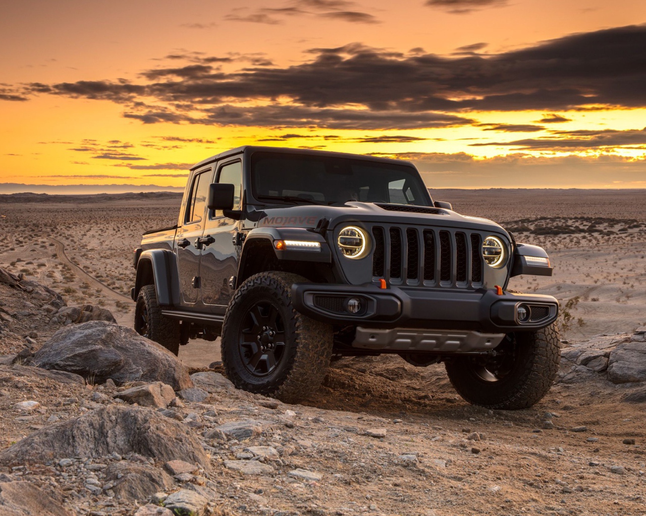 Черный внедорожник Jeep Gladiator Mojave, 2020 года в пустыне на закате