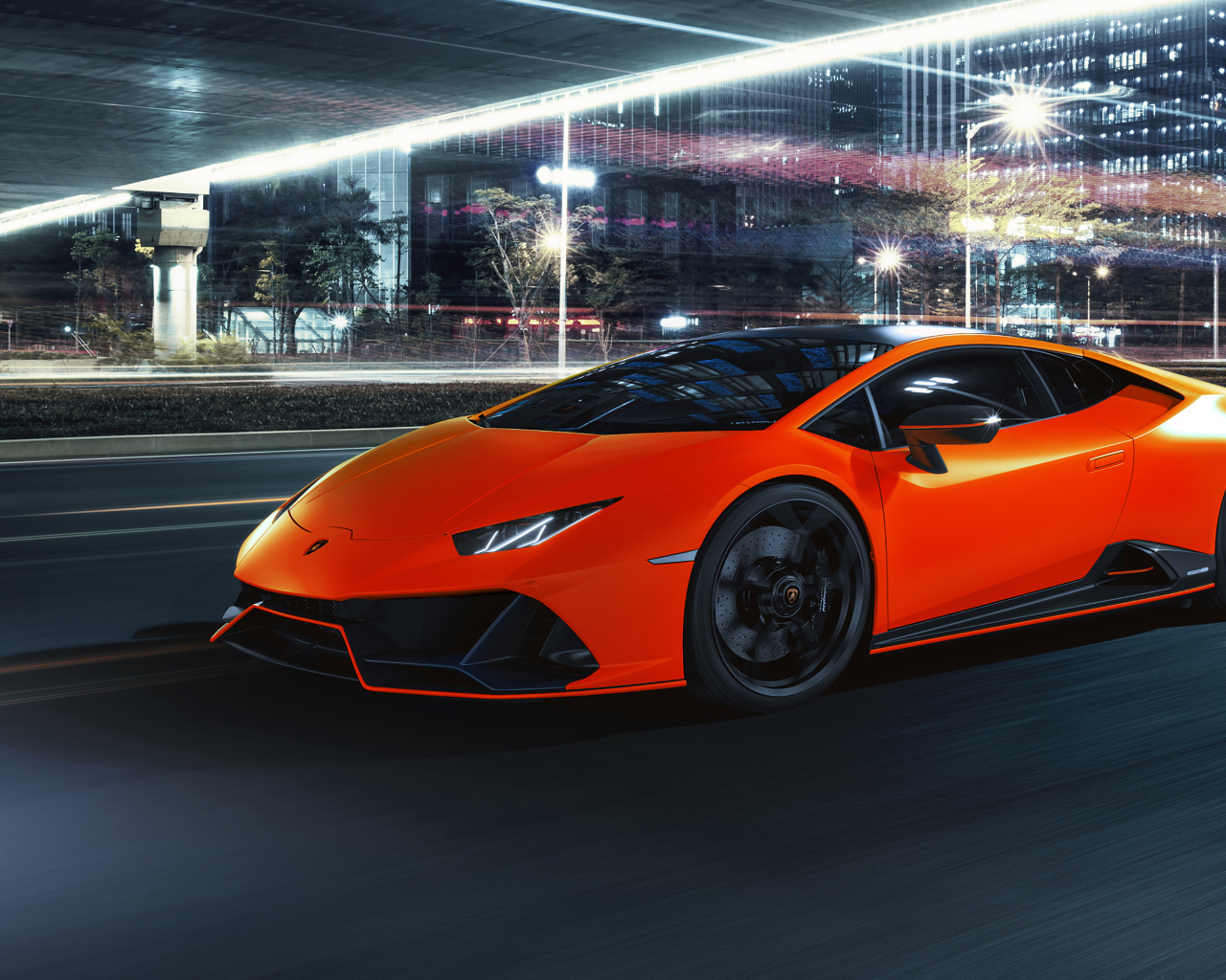 Оранжевый автомобиль Lamborghini Huracán EVO 2021 года на фоне города