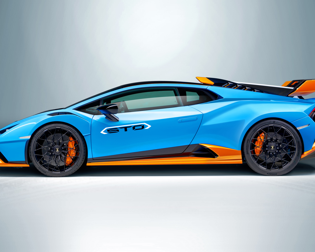 Голубой автомобиль Lamborghini Huracán STO 2021 года вид сбоку