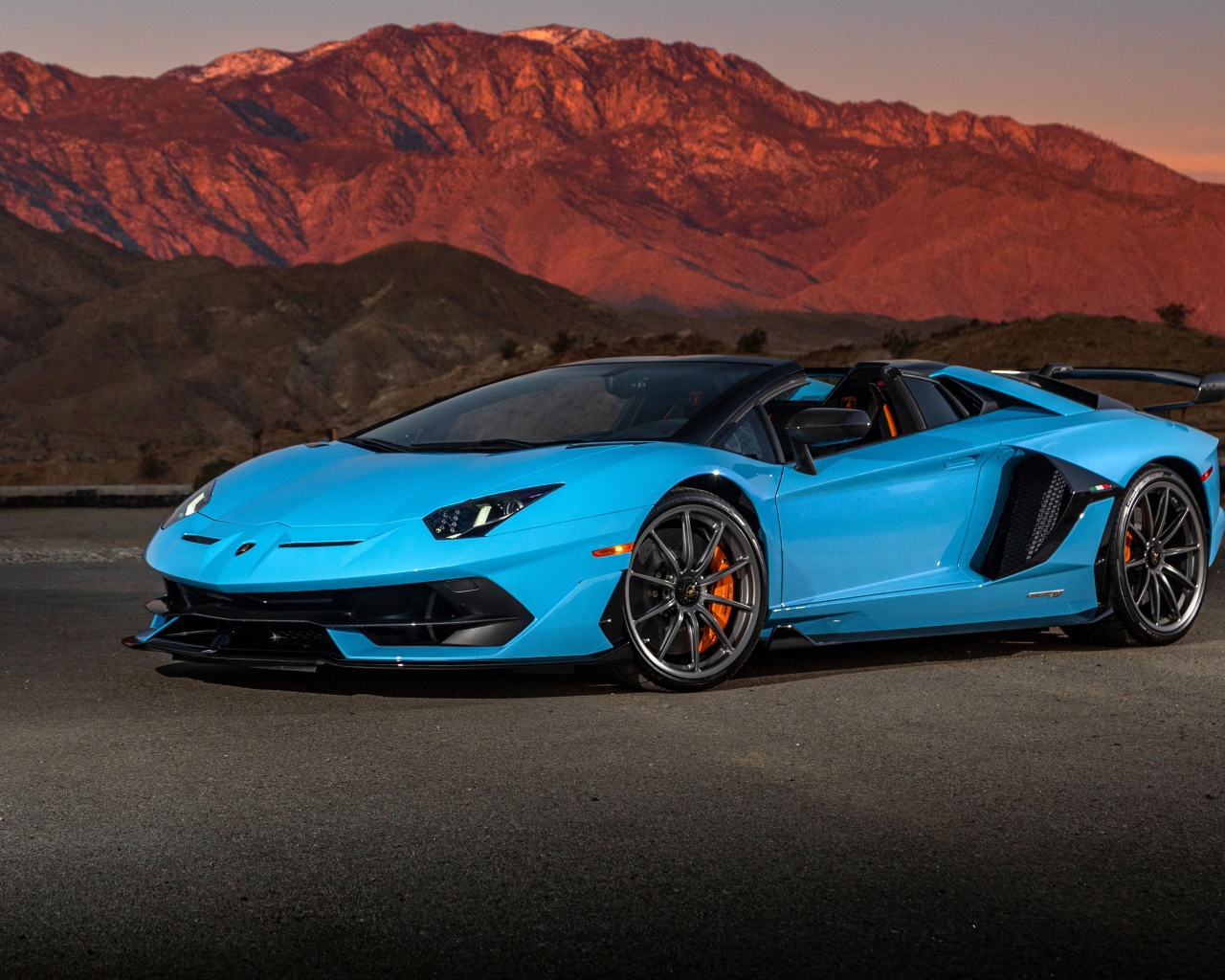 Голубой спортивный автомобиль Lamborghini Aventador SVJ Roadster, 2020 года на фоне гор