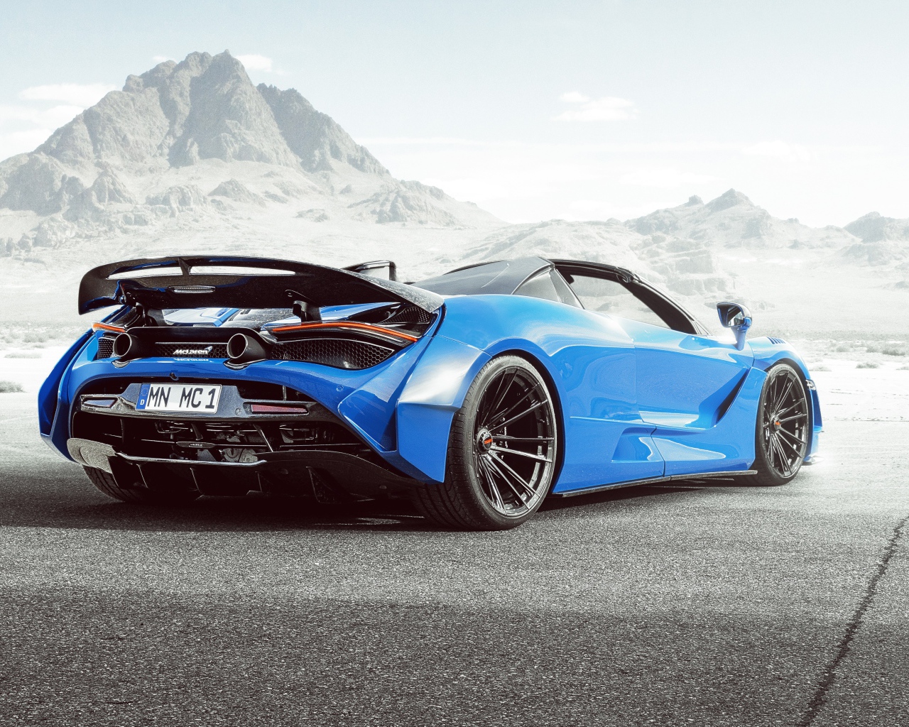 Голубой автомобиль  McLaren 720S Spider N-Largo 2020 года вид сзади на фоне гор 