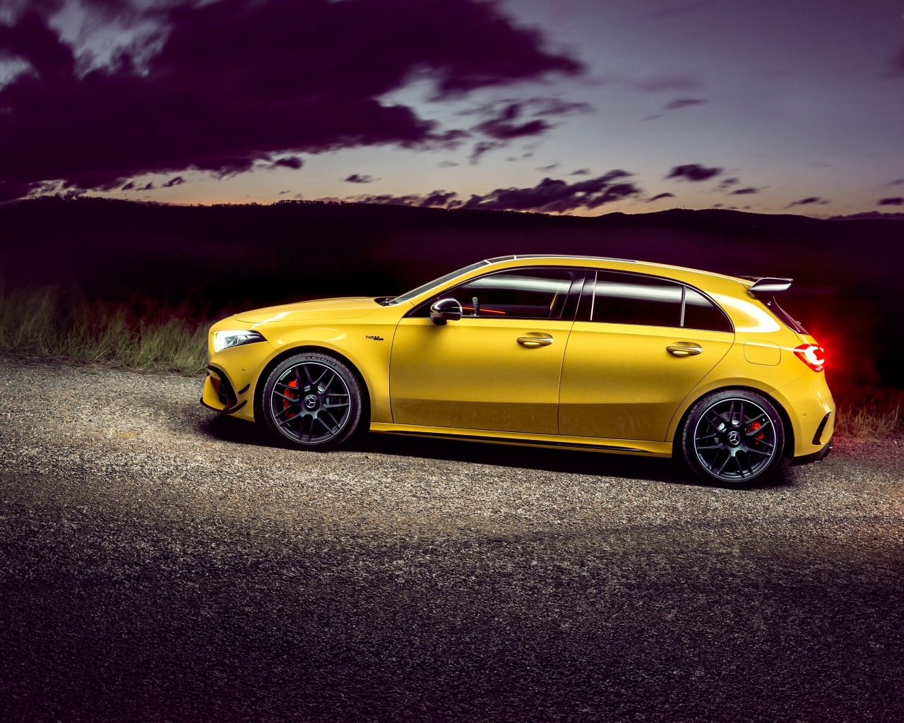 Желтый автомобиль Mercedes-AMG A 45 S, 2020 года на дороге в сумерках 