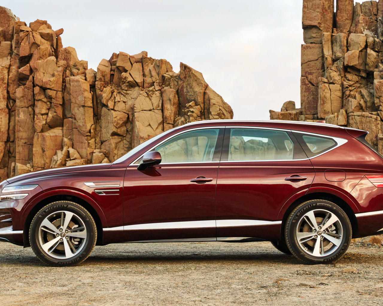 Бордовый автомобиль Genesis GV80 2.5T 2020 года на фоне гор