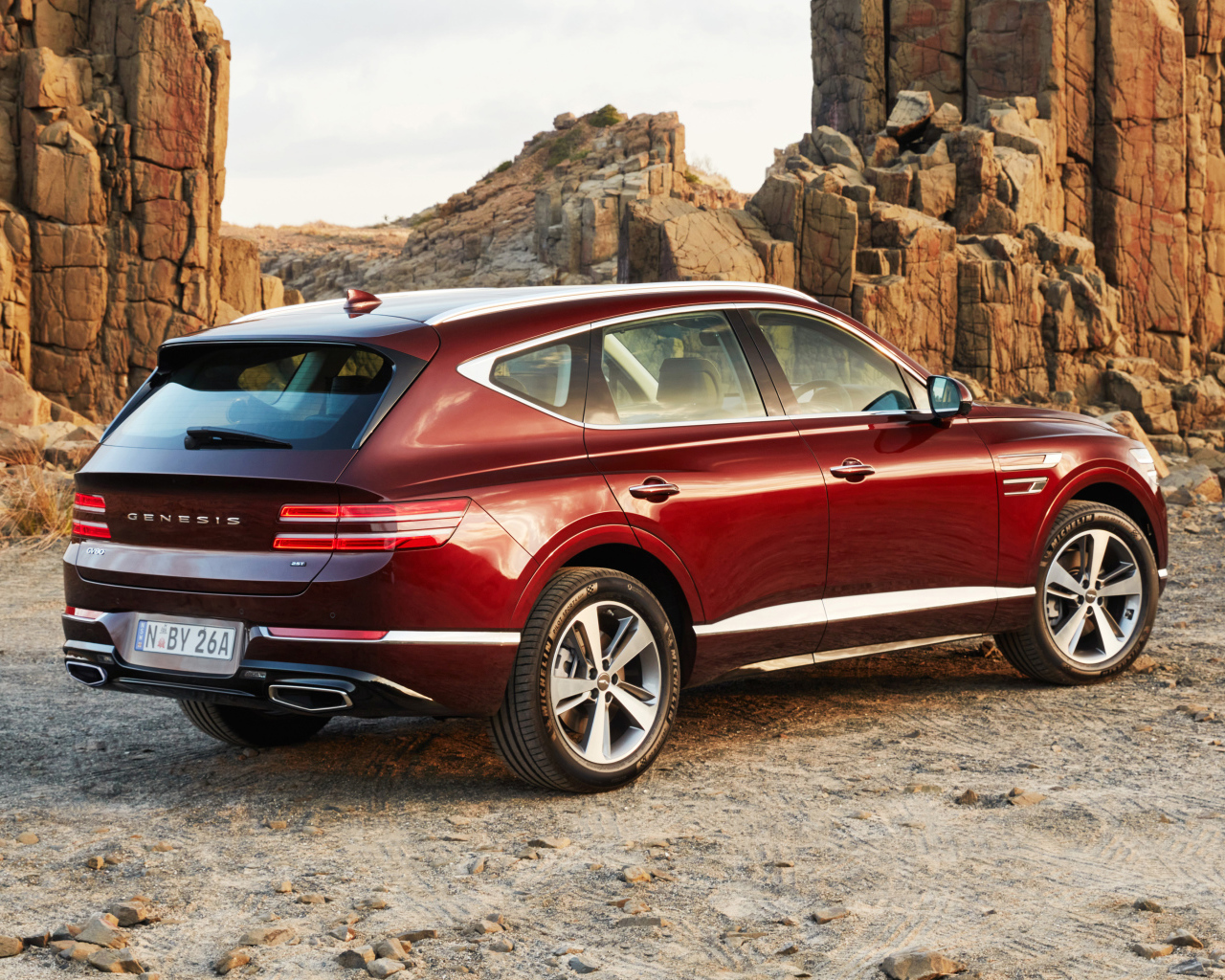 Красный автомобиль Genesis GV80 2.5T 2020 года на фоне гор