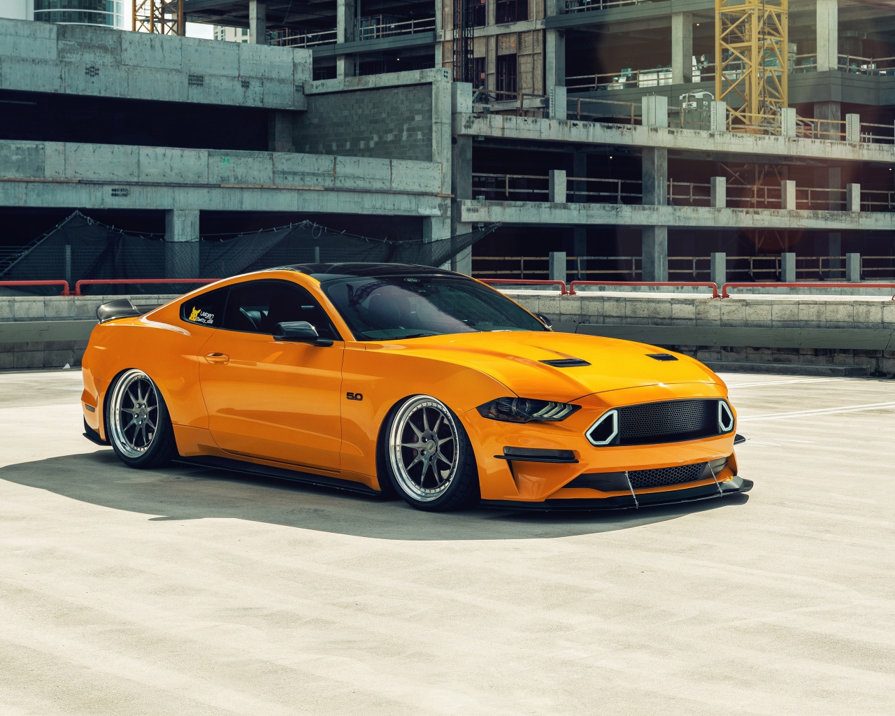 Оранжевый автомобиль Mustang у заброшенного здания 