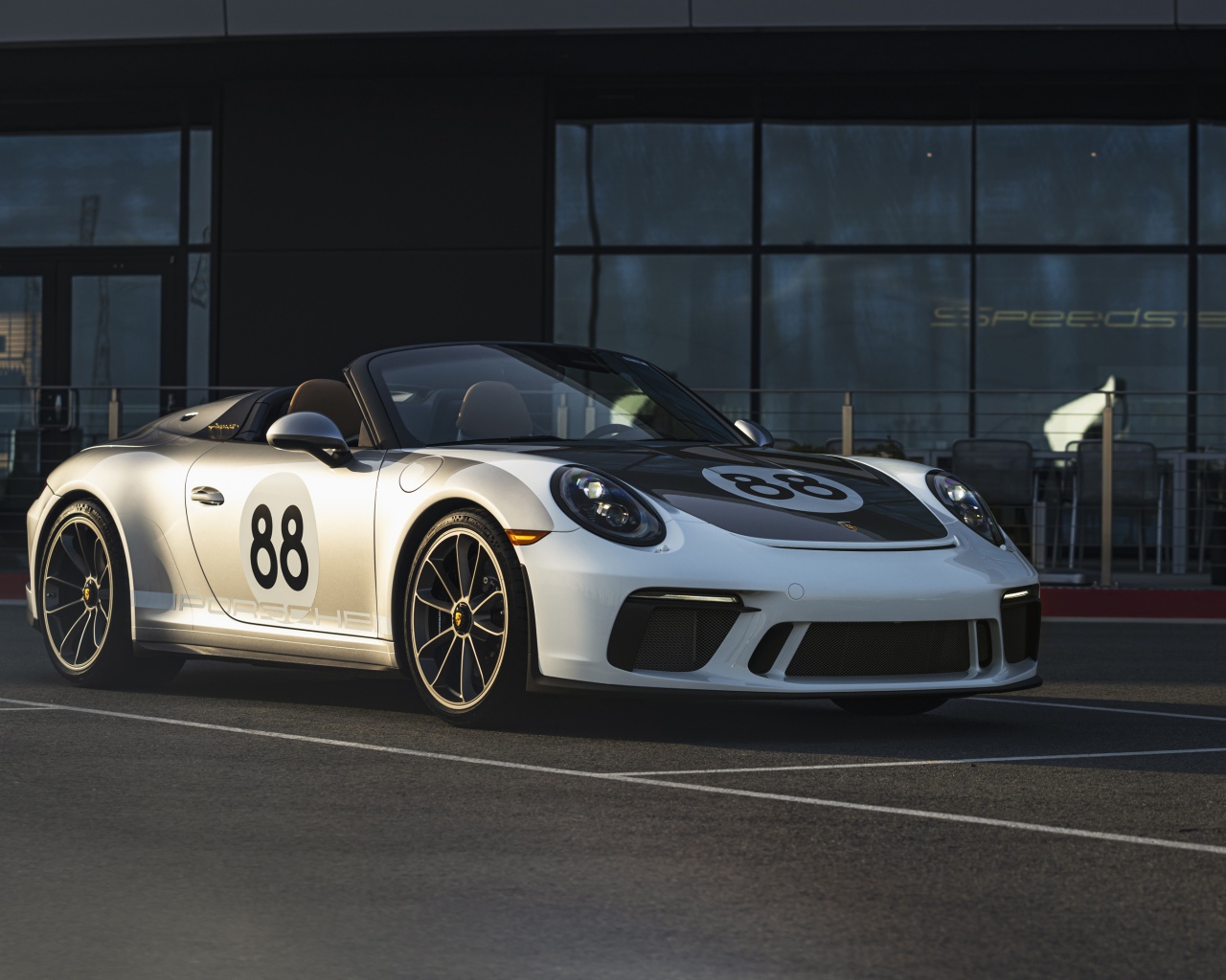 Спортивный автомобиль Porsche 911, 2019 года у стеклянного здания