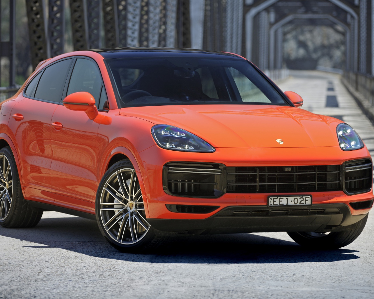 Оранжевый внедорожник Porsche Cayenne Turbo Coupe 2019 года на мосту