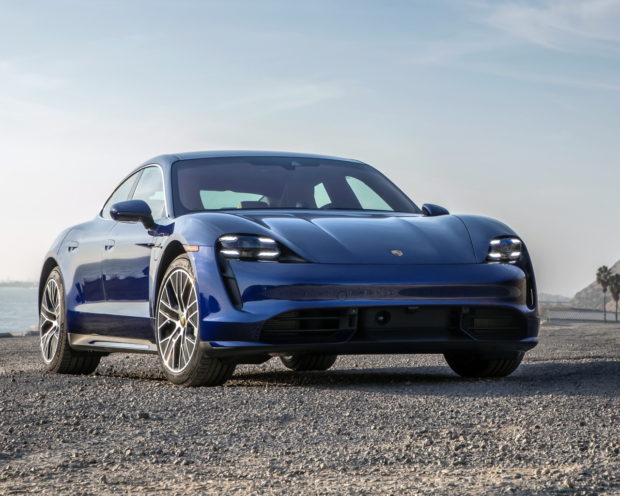 Синий автомобиль  Porsche Taycan Turbo, 2020 года у океана