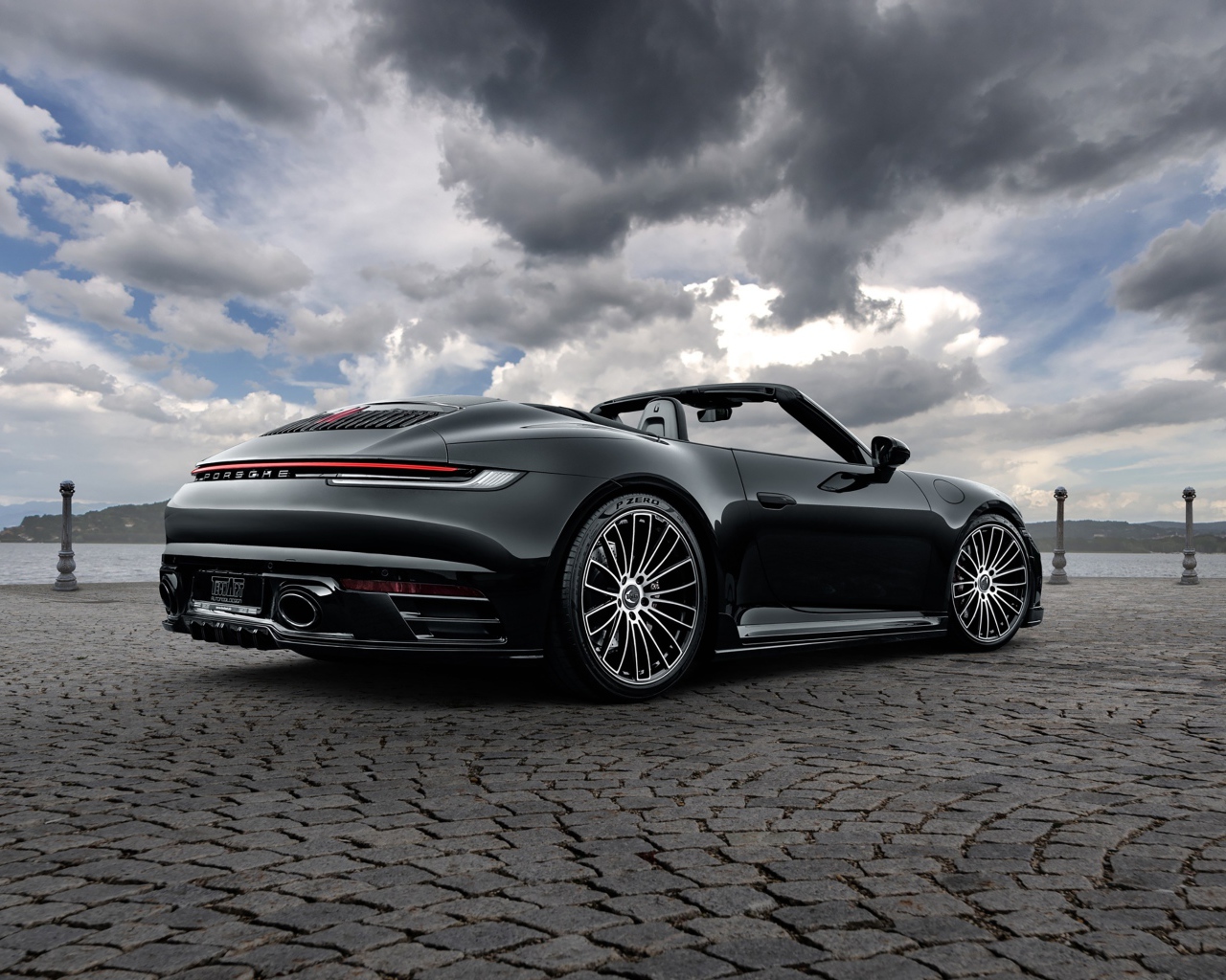 Черный автомобиль Porsche 911 Carrera 4S Cabriolet 2020 года под грозовым небом