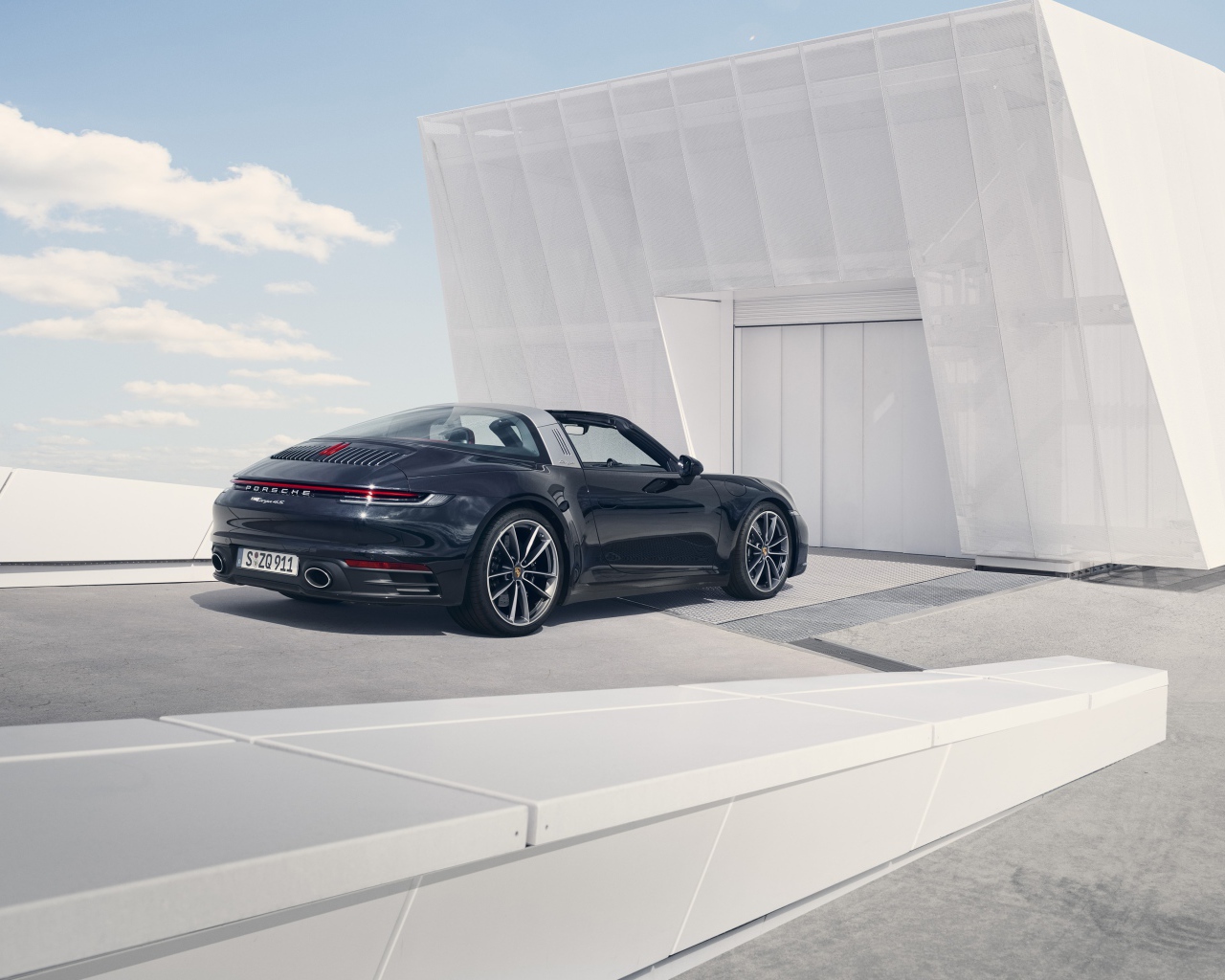 Черный автомобиль Porsche 911 Targa 4S 2020 года у гаража 