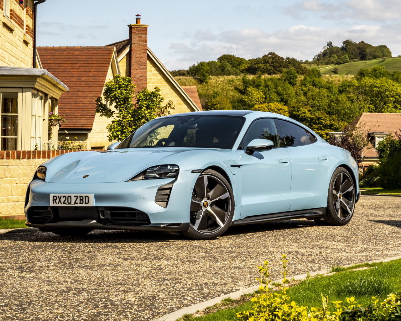 Голубой автомобиль Porsche Taycan 4S 2021 года у дома вид спереди