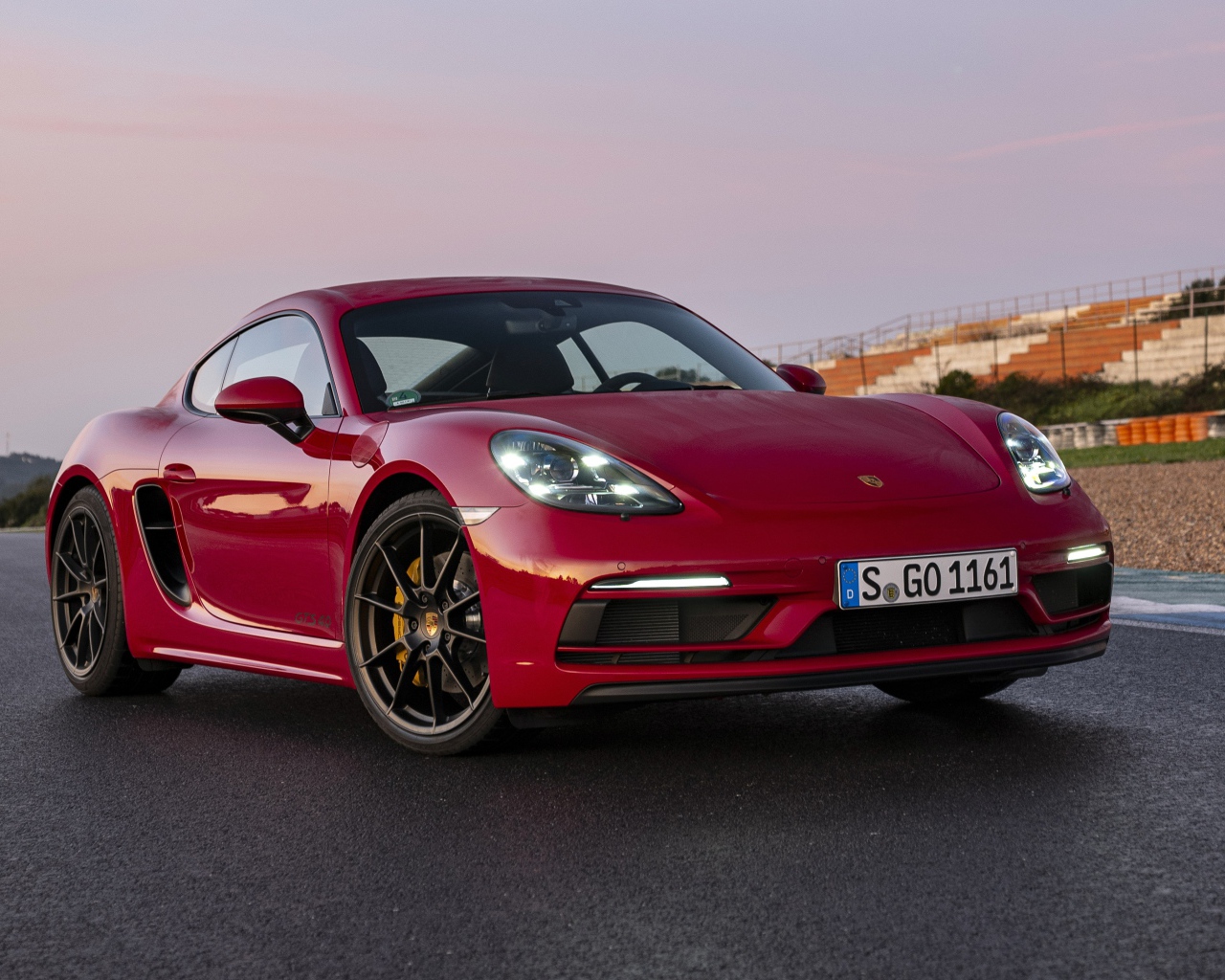 Красный автомобиль Porsche 718 Cayman GTS 4,  2020  года на стадионе