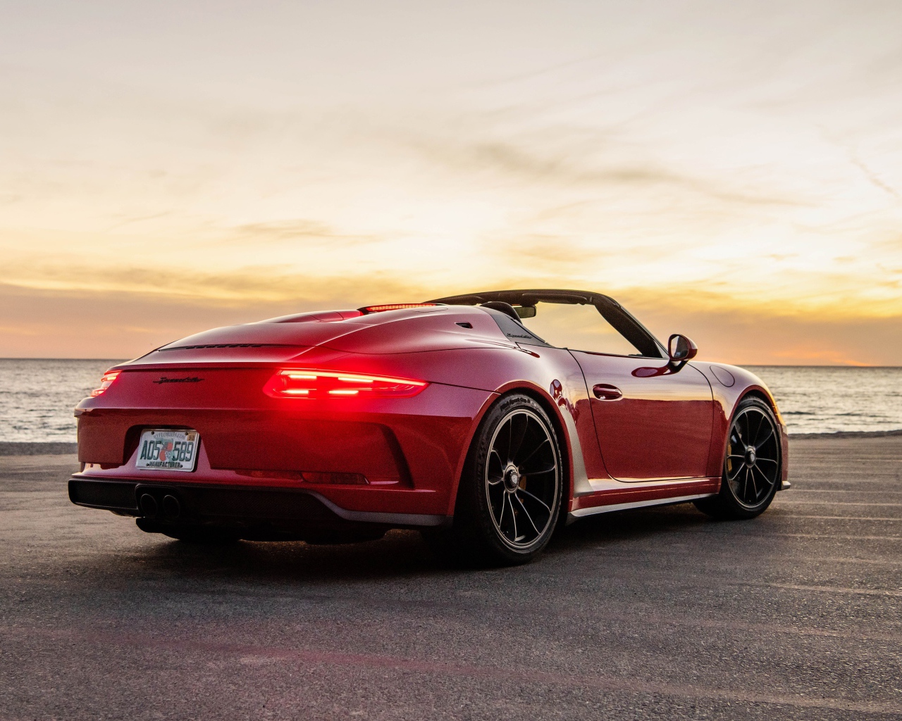 Красный автомобиль Porsche 911 Speedster, 2019 года у моря на закате
