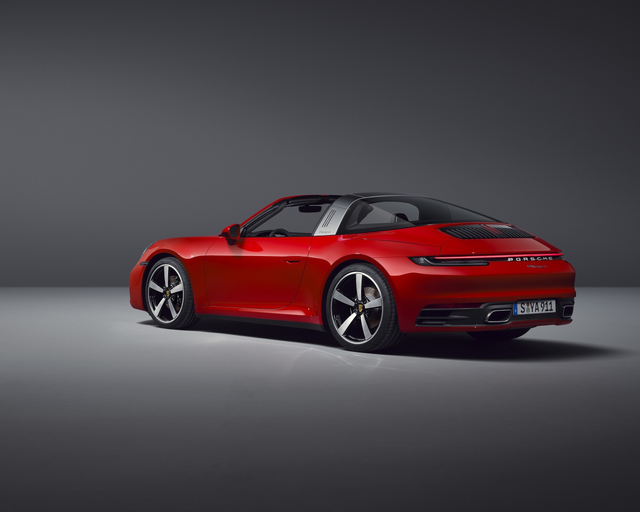 Красный автомобиль Porsche 911 Targa 4, 2020 года на сером фоне вид сзади