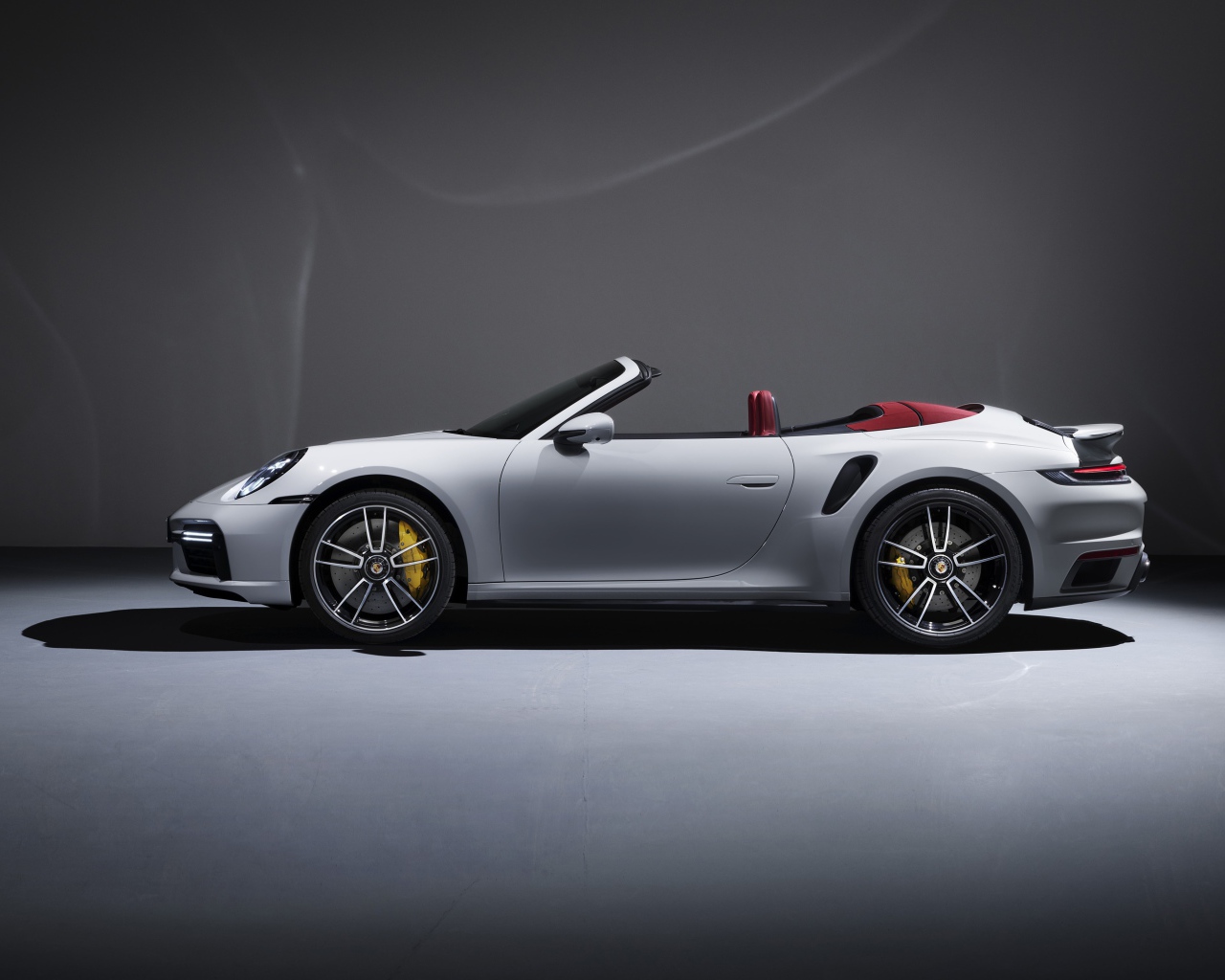 Белый автомобиль Porsche 911 Turbo S Cabriolet 2020 года на сером фоне