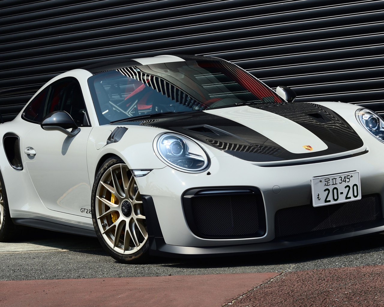 Белый автомобиль Porsche 911 GT2 RS  у черной стены