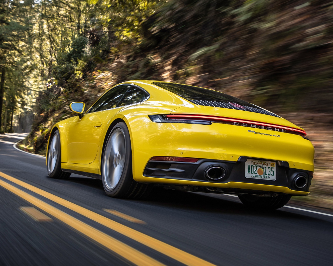 Желтый автомобиль  Porsche 911 Carrera 4S, 2020 года на трассе 