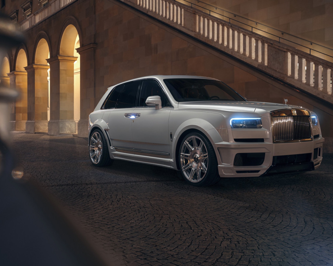 Белый автомобиль  Rolls-Royce Cullinan 2020 года у лестницы