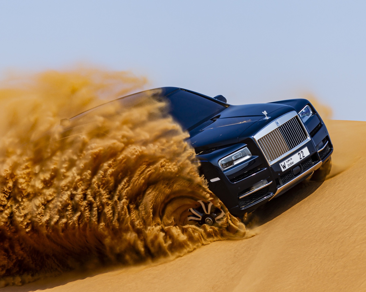 Черный Rolls-Royce Cullinan дрифтует по песку 