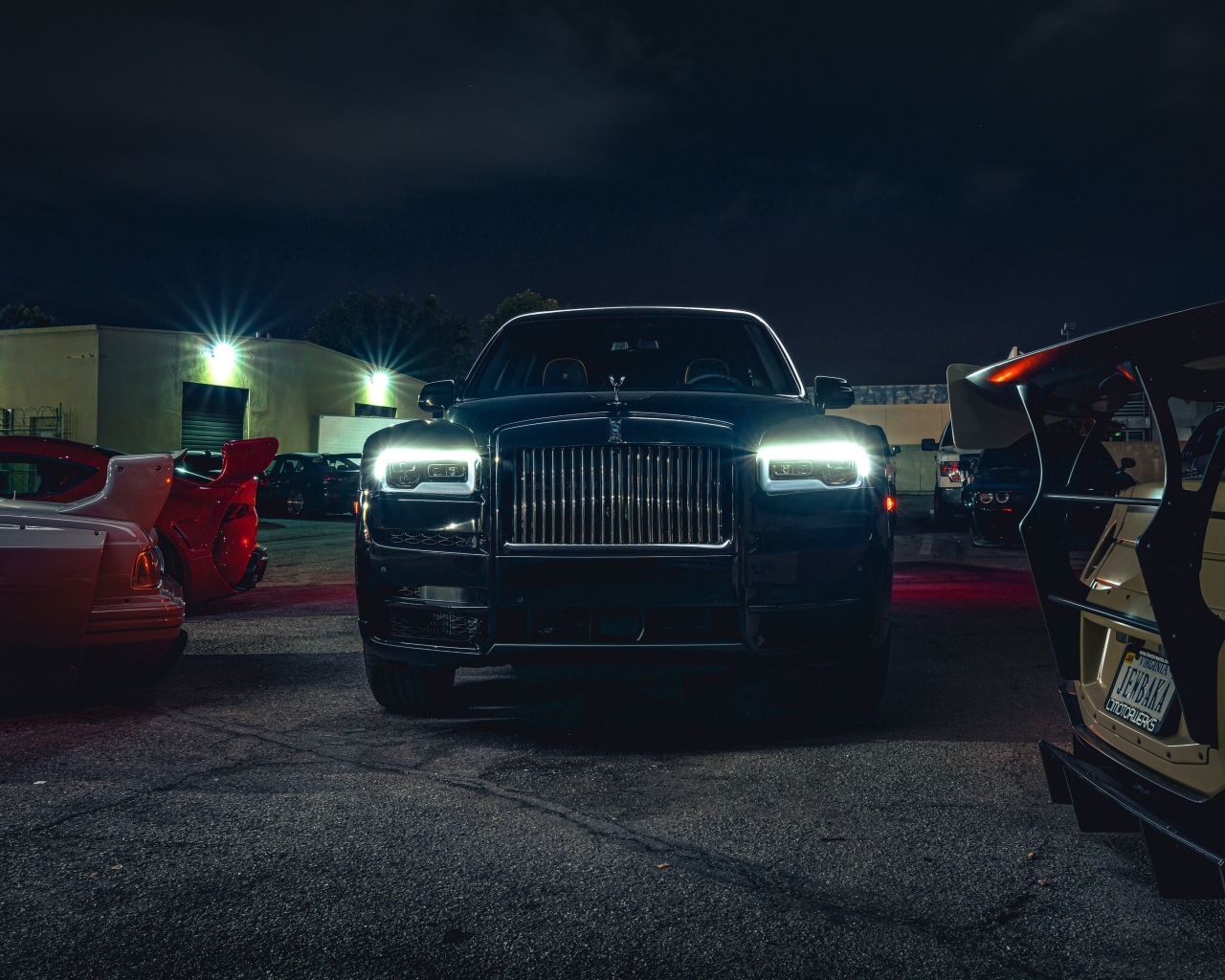 Черный дорогой автомобиль  Rolls-Royce Cullinan, 2020 года с включенными фарами