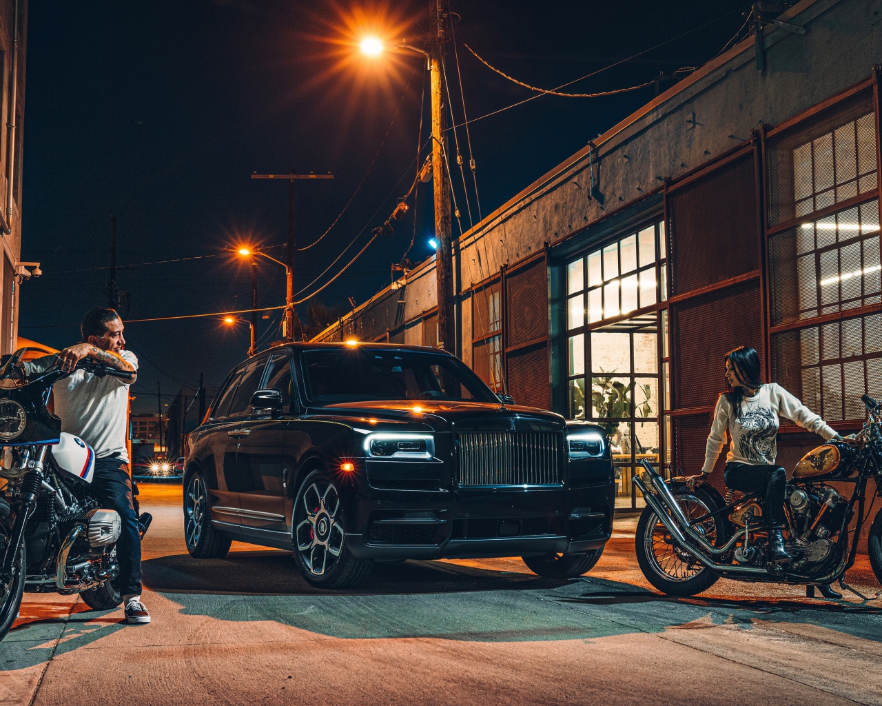 Черный стильный автомобиль Rolls-Royce Cullinan на улице города с байкерами