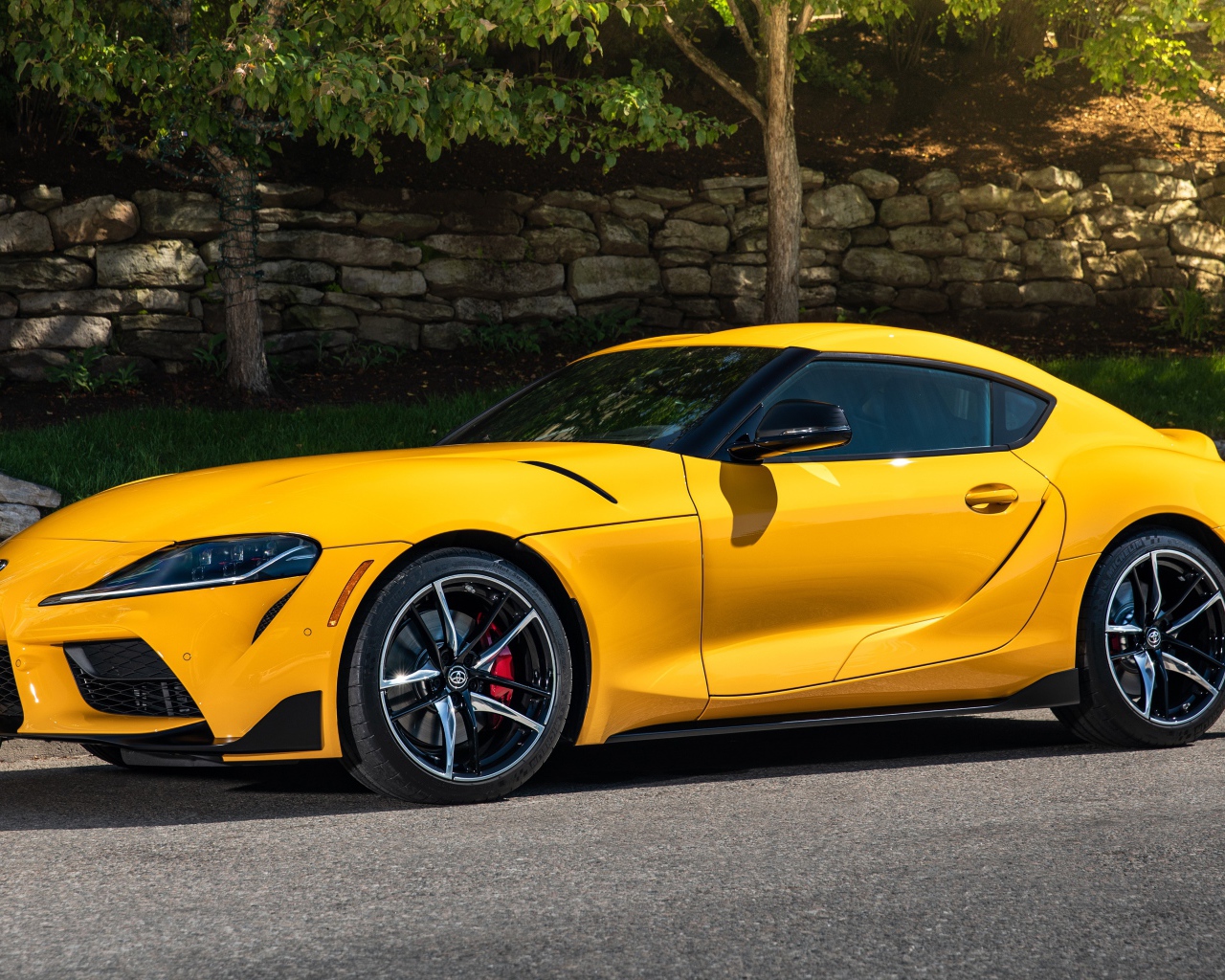Желтый автомобиль Toyota GR Supra,ю 2021 года у стены