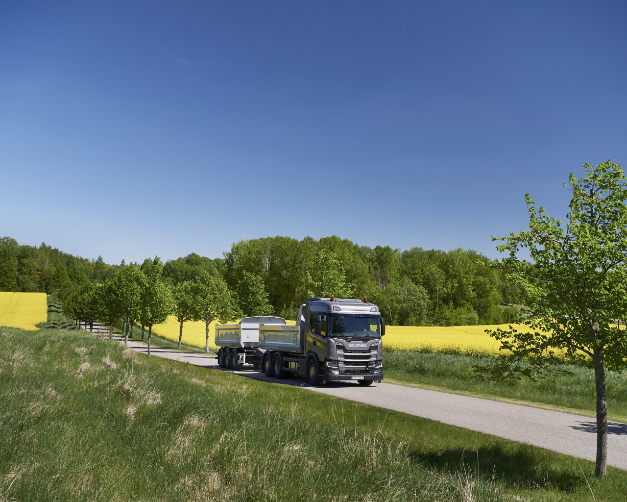 Грузовик Scania Trucks на трассе у поля