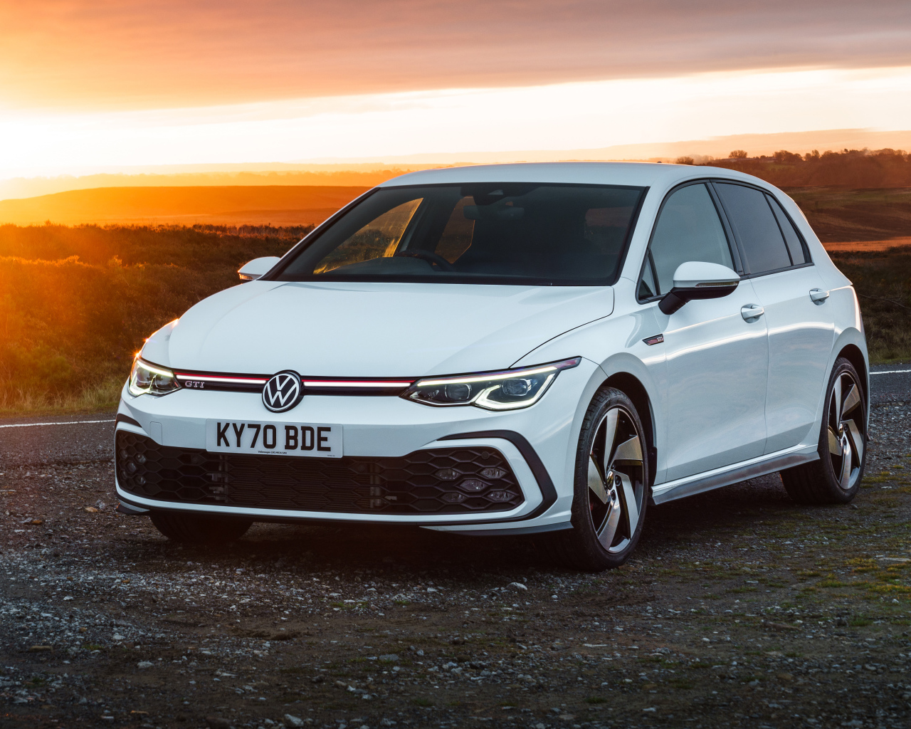 Белый автомобиль Volkswagen Golf GTI 2020 года на закате солнца