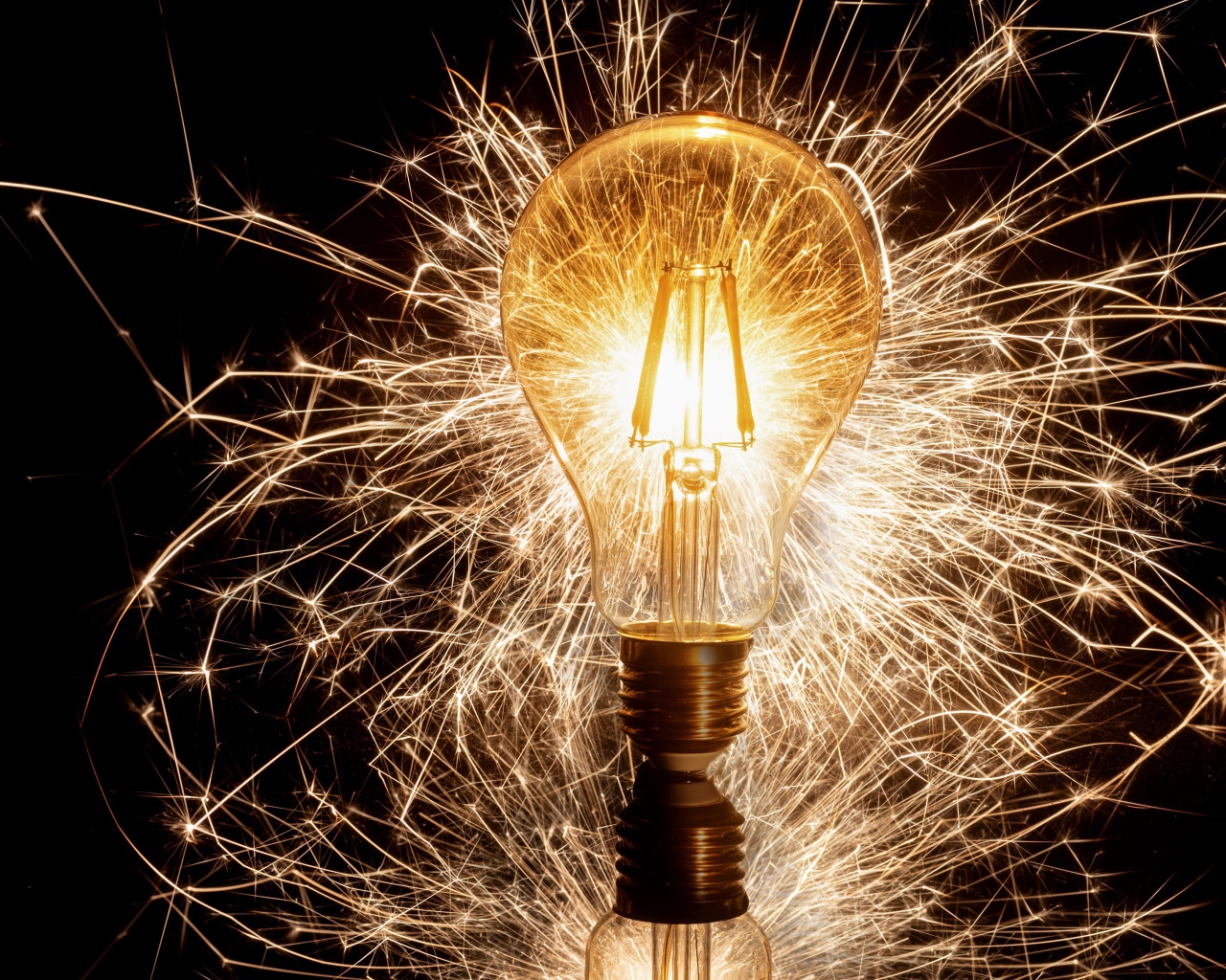 A lit lamp on a black background with sparks
