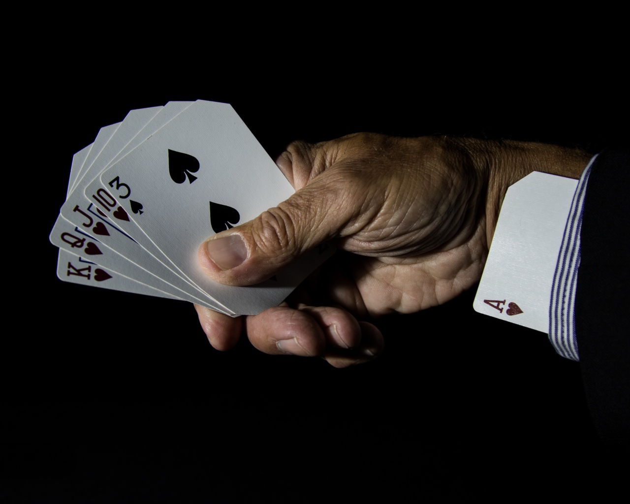 Туз в рукаве у шулера на черном фоне 