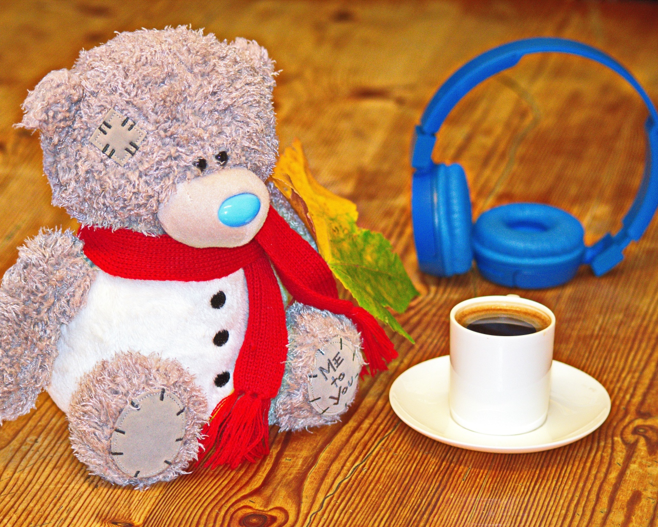 Медведь на столе с чашкой кофе и наушниками 