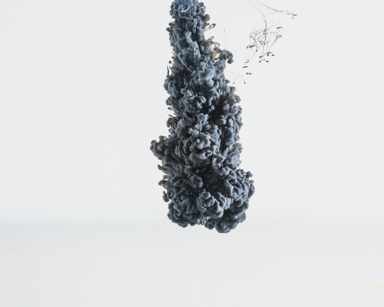 Черная краска растворяется в воде на белом фоне 