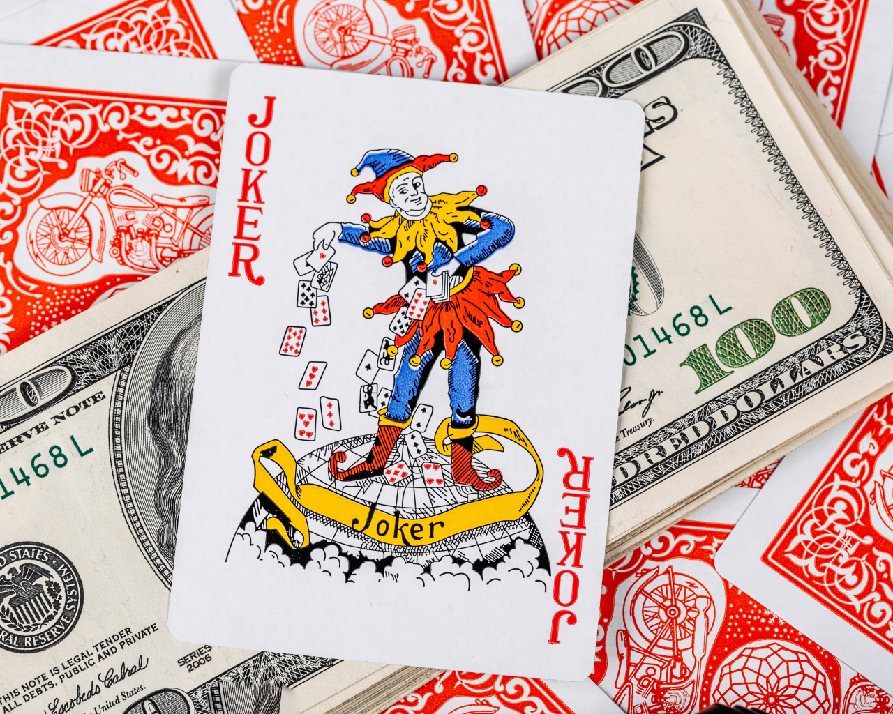 Карточный Джокер и пачка стодолларовых купюр