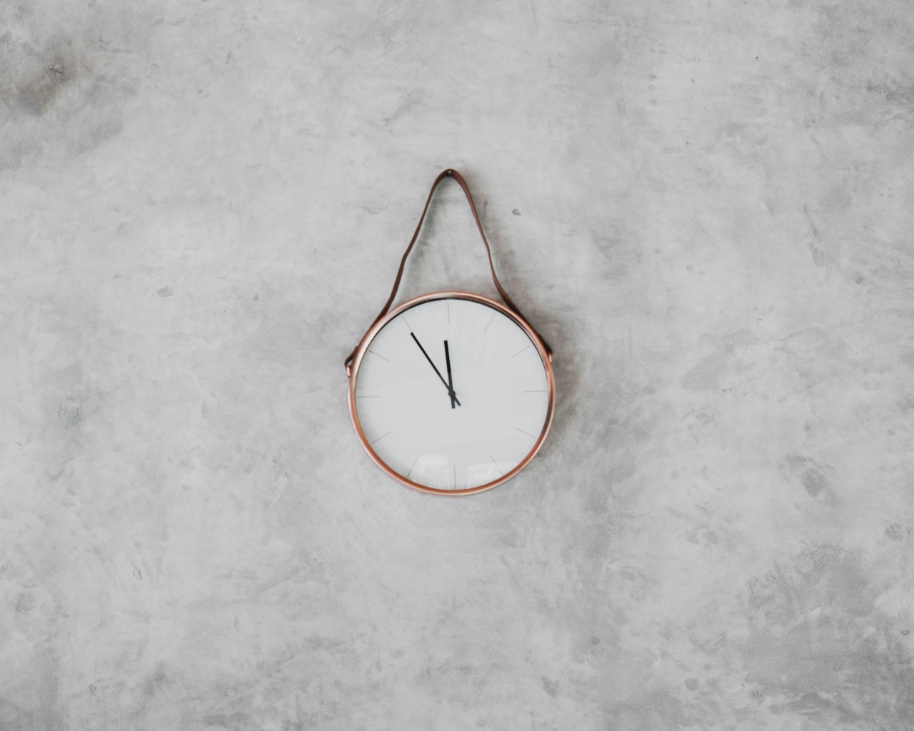 Часы с черными стрелками висят на серой стене 