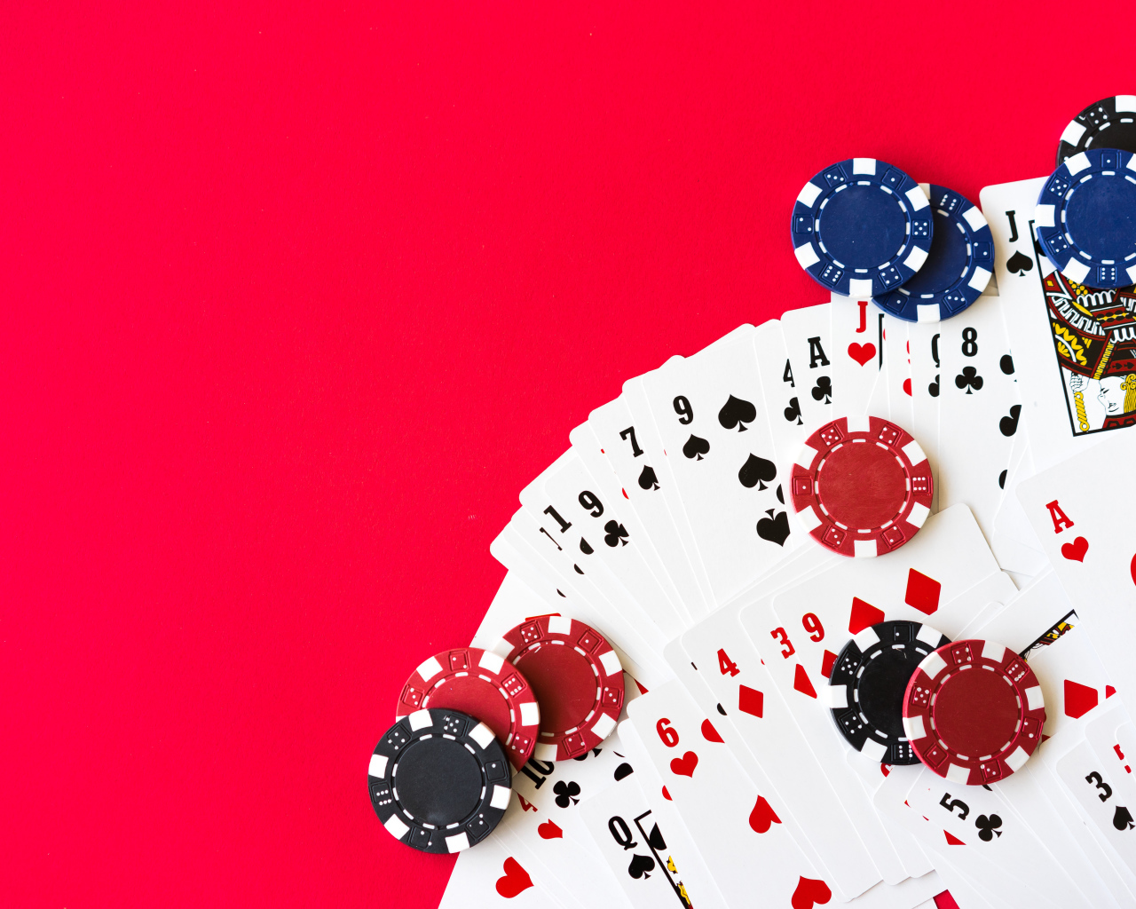 Колода карт и фишки для игры в покер на красном фоне