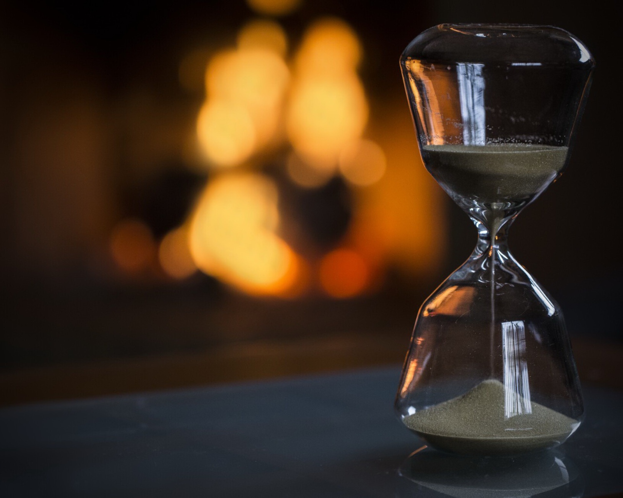 Стеклянные песочные часы на столе 