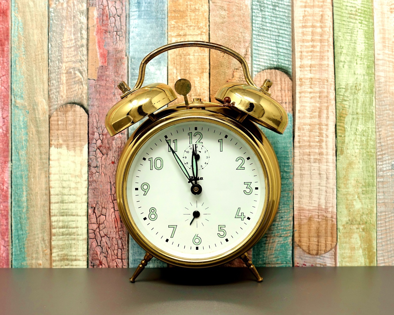 Золотой будильник стоит у стены 