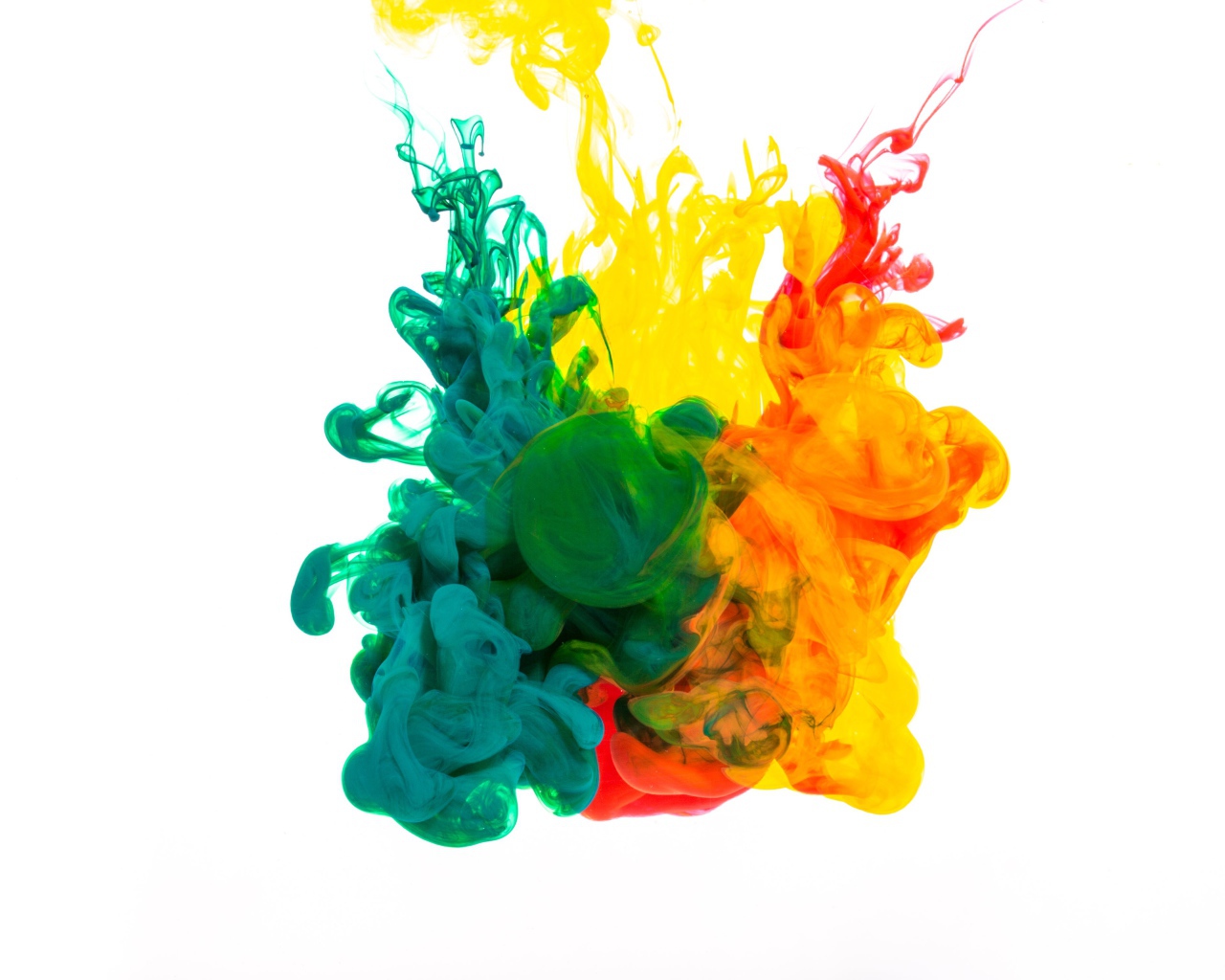 Зеленая и желтая краска растворяются в воде на белом фоне