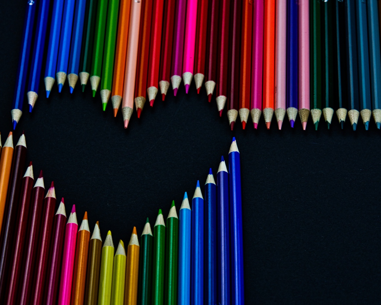 Сердце из разноцветных карандашей на черном фоне